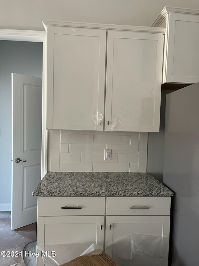 2958 Old Berwick St SW, Shallotte, NC 28470 - kitchen with tasteful backsplash, white cabinetry, dark stone counters, and freestanding refrigerator