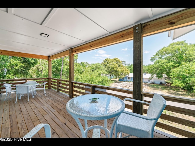 119 NE 27th St, Oak Island, NC 28465 - wooden terrace with outdoor dining area and view of scattered trees