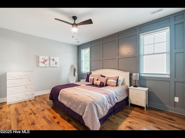 119 NE 27th St, Oak Island, NC 28465 - bedroom featuring a decorative wall, light wood finished floors, baseboards, and a ceiling fan
