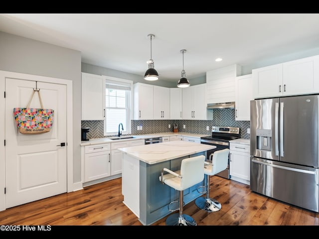 119 NE 27th St, Oak Island, NC 28465 - kitchen featuring appliances with stainless steel finishes, a sink, under cabinet range hood, a kitchen island, and backsplash