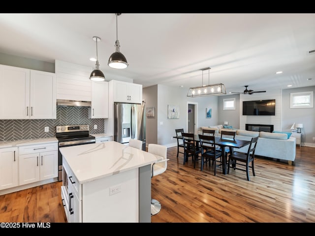 119 NE 27th St, Oak Island, NC 28465 - kitchen featuring stainless steel appliances, a kitchen island, decorative backsplash, open floor plan, and a ceiling fan