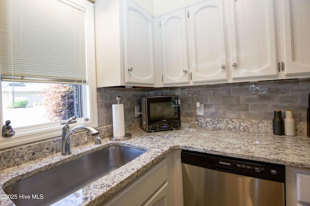 940 Linden Rd Unit 19, Pinehurst, NC 28374 - kitchen with stainless steel dishwasher, a sink, white cabinetry, tasteful backsplash, and light stone countertops