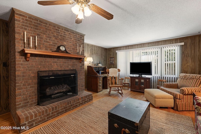 1606 Palm St, Goldsboro, NC 27530 - living area featuring a textured ceiling, wood finished floors, a ceiling fan, a brick fireplace, and wood walls