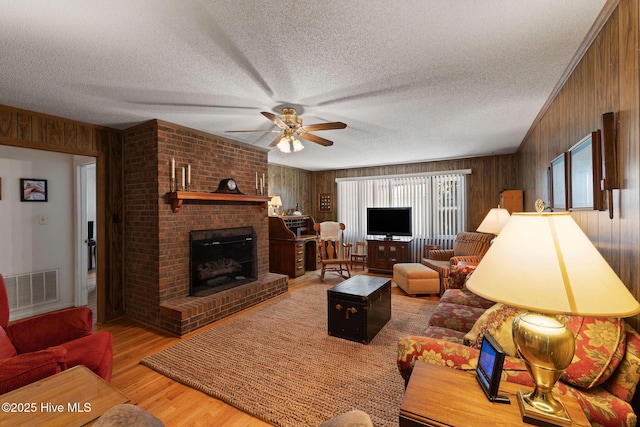 1606 Palm St, Goldsboro, NC 27530 - living room with wooden walls, ceiling fan, wood finished floors, a textured ceiling, and a fireplace