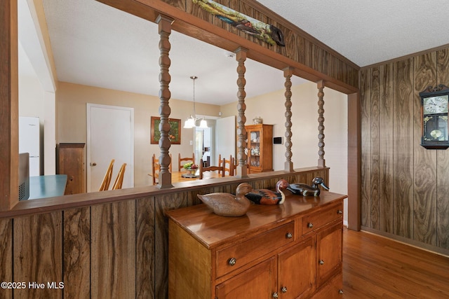1606 Palm St, Goldsboro, NC 27530 - kitchen featuring wood finished floors, brown cabinetry, wood walls, a chandelier, and hanging light fixtures