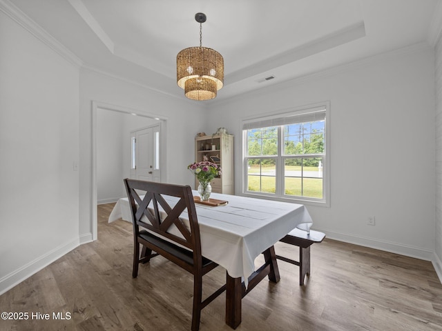 608 Creek Ct, Swansboro, NC 28584 - dining room featuring a tray ceiling, a chandelier, wood finished floors, baseboards, and ornamental molding