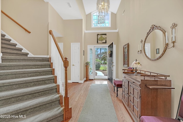 3856 Harmony Cir, Southport, NC 28461 - entryway featuring light wood-type flooring, stairs, a chandelier, baseboards, and high vaulted ceiling
