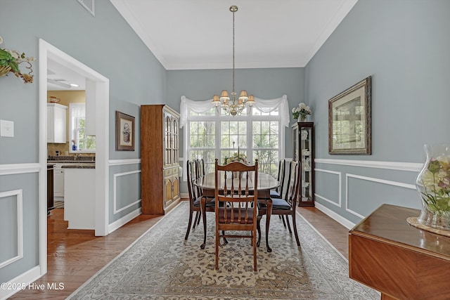 3856 Harmony Cir, Southport, NC 28461 - dining space with a chandelier, wood finished floors, ornamental molding, wainscoting, and a decorative wall