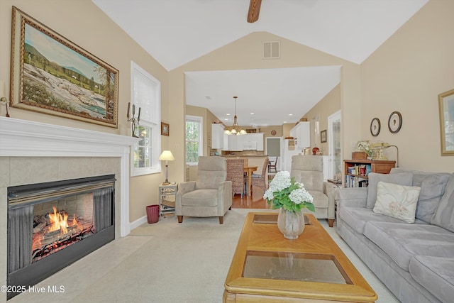 3856 Harmony Cir, Southport, NC 28461 - living room with a tiled fireplace, a chandelier, vaulted ceiling, and light colored carpet