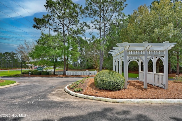 3856 Harmony Cir, Southport, NC 28461 - surrounding community featuring a pergola, view of scattered trees, and asphalt driveway