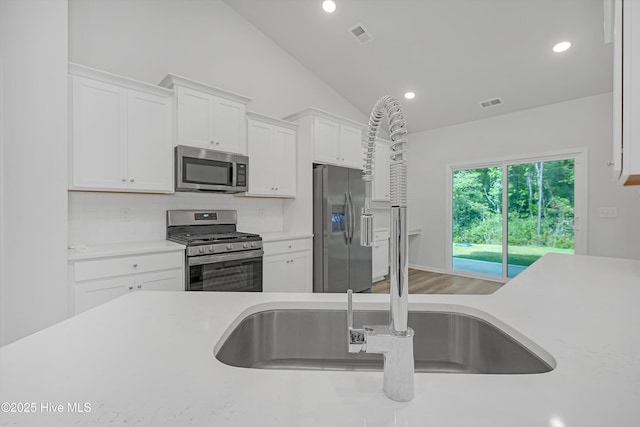 6437 Twinspur Ct SW, Ocean Isle Beach, NC 28469 - kitchen featuring stainless steel appliances, light countertops, lofted ceiling, tasteful backsplash, and white cabinets
