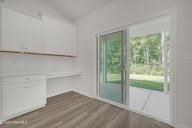 6437 Twinspur Ct SW, Ocean Isle Beach, NC 28469 - unfurnished dining area featuring light wood finished floors, built in desk, and vaulted ceiling