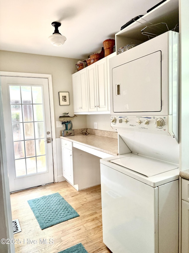 2210 Klein Rd, Wilmington, NC 28405 - laundry area featuring stacked washer and clothes dryer, cabinet space, and light wood-style floors