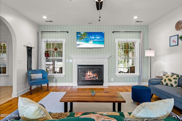 1682 Gores Landing Rd SW, Ocean Isle Beach, NC 28469 - living area featuring wood finished floors, baseboards, a fireplace with flush hearth, arched walkways, and ceiling fan