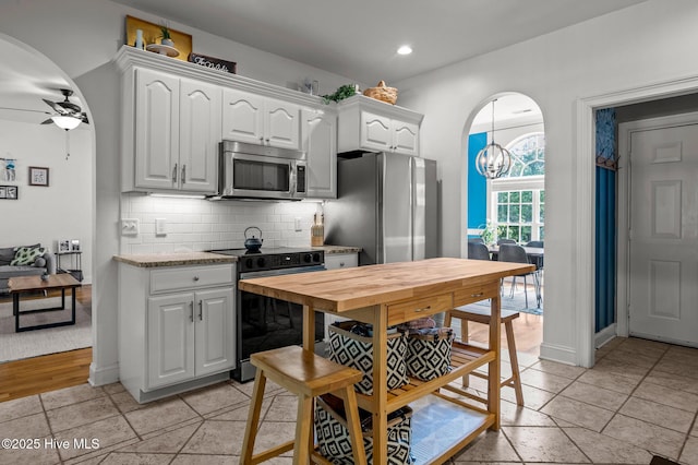 1682 Gores Landing Rd SW, Ocean Isle Beach, NC 28469 - kitchen with stainless steel appliances, white cabinetry, decorative backsplash, ceiling fan, and arched walkways
