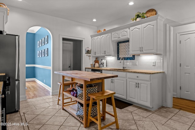 1682 Gores Landing Rd SW, Ocean Isle Beach, NC 28469 - kitchen with freestanding refrigerator, a sink, white cabinetry, tasteful backsplash, and recessed lighting