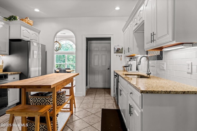 1682 Gores Landing Rd SW, Ocean Isle Beach, NC 28469 - kitchen featuring a sink, decorative backsplash, light tile patterned floors, white cabinetry, and light stone countertops