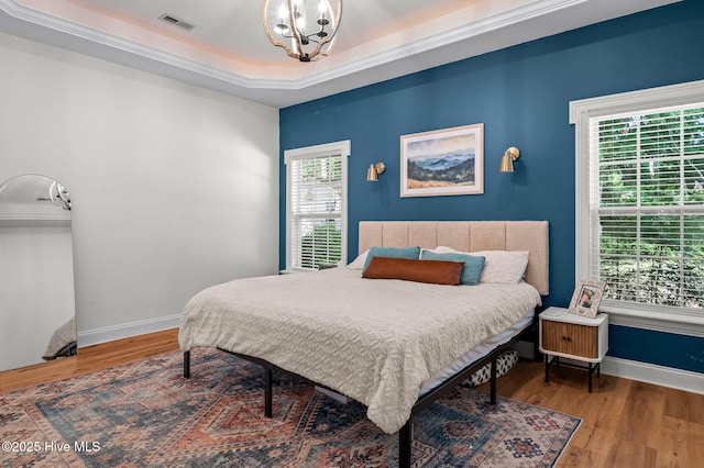1682 Gores Landing Rd SW, Ocean Isle Beach, NC 28469 - bedroom with wood finished floors, a tray ceiling, a chandelier, and baseboards