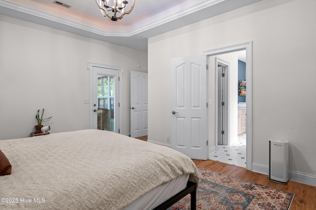 1682 Gores Landing Rd SW, Ocean Isle Beach, NC 28469 - bedroom featuring a chandelier, wood finished floors, a tray ceiling, and baseboards