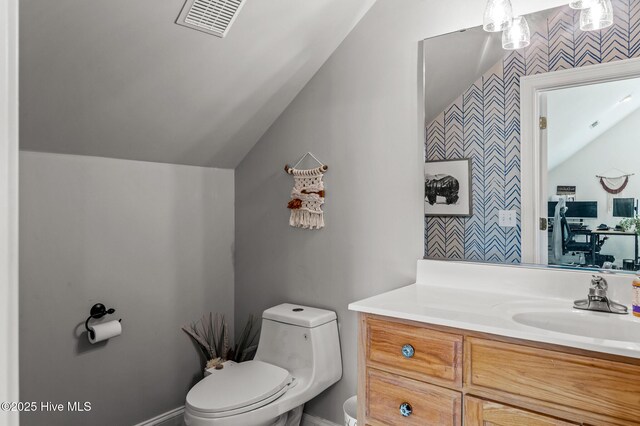 1682 Gores Landing Rd SW, Ocean Isle Beach, NC 28469 - bathroom featuring lofted ceiling, wallpapered walls, toilet, vanity, and an accent wall