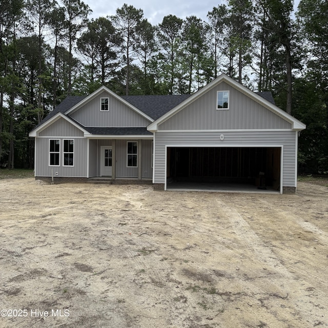 129 Bayview Trl, Edenton, NC 27932 - view of front facade with dirt driveway, a shingled roof, an attached garage, and covered porch