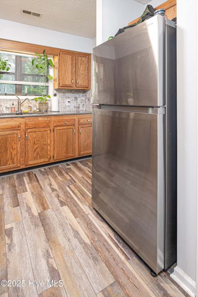 923 Persimmon Pl, Winterville, NC 28590 - kitchen with freestanding refrigerator, light wood finished floors, a sink, brown cabinets, and a textured ceiling