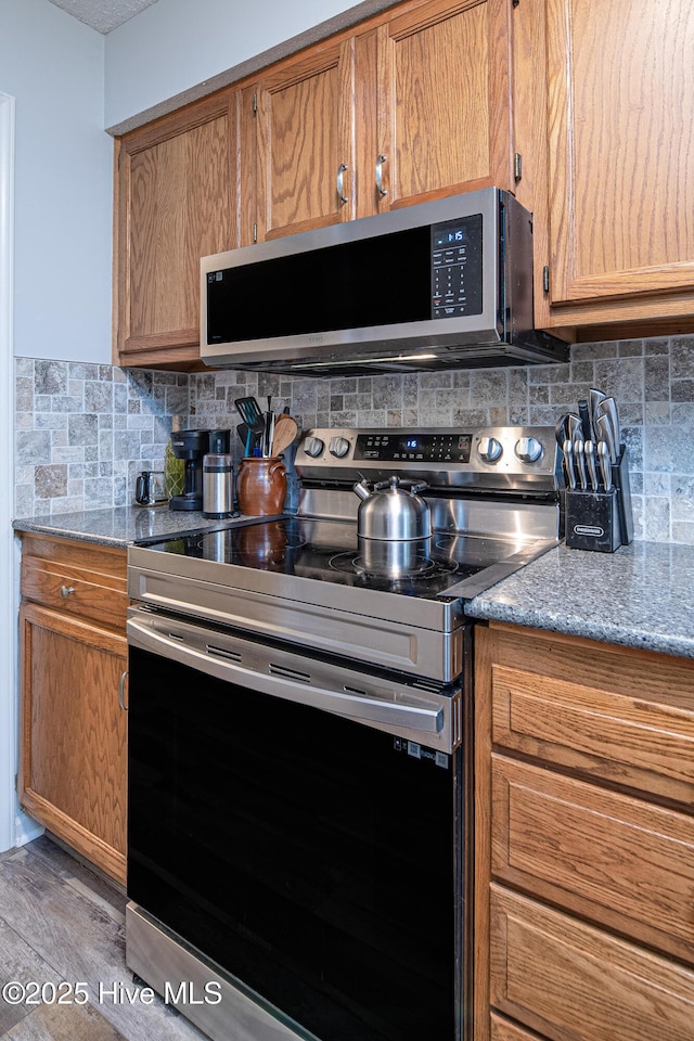 923 Persimmon Pl, Winterville, NC 28590 - kitchen with appliances with stainless steel finishes, decorative backsplash, light wood-style flooring, light stone counters, and brown cabinetry