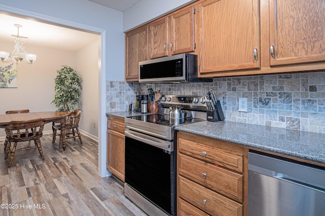 923 Persimmon Pl, Winterville, NC 28590 - kitchen with appliances with stainless steel finishes, tasteful backsplash, light wood finished floors, a chandelier, and light stone counters