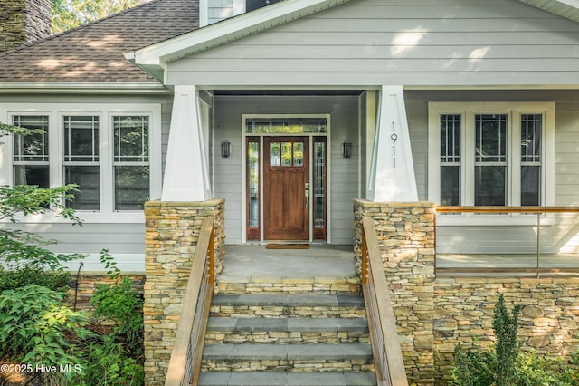 1911 Middle Sound Loop Rd, Wilmington, NC 28411 - view of exterior entry with a chimney, stone siding, roof with shingles, and a porch