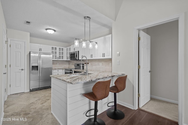 4109 Breezewood Dr Unit 204, Wilmington, NC 28412 - kitchen with appliances with stainless steel finishes, light stone counters, a peninsula, glass insert cabinets, and white cabinetry