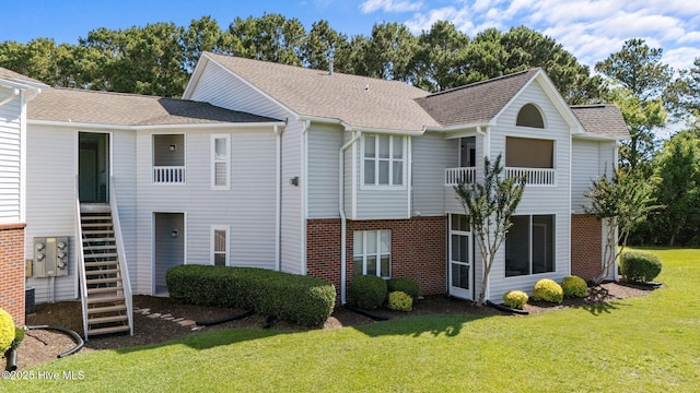 4109 Breezewood Dr Unit 204, Wilmington, NC 28412 - view of front of home with stairs, brick siding, a front yard, a balcony, and a shingled roof