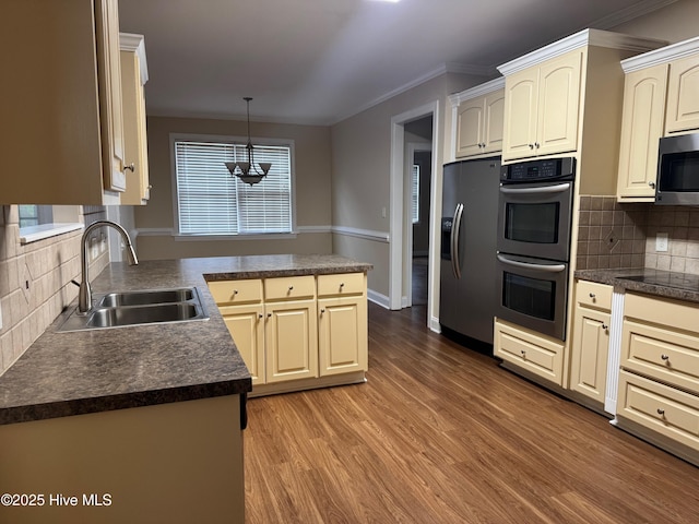 315 Hunters Creek Dr, Goldsboro, NC 27534 - kitchen with appliances with stainless steel finishes, a sink, dark countertops, cream cabinets, and wood finished floors
