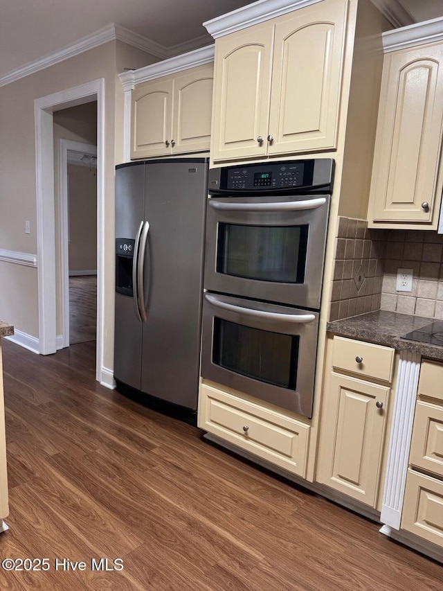 315 Hunters Creek Dr, Goldsboro, NC 27534 - kitchen with appliances with stainless steel finishes, cream cabinetry, dark wood finished floors, dark countertops, and crown molding