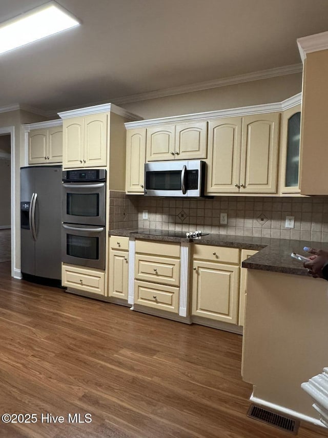 315 Hunters Creek Dr, Goldsboro, NC 27534 - kitchen featuring stainless steel appliances, crown molding, dark wood-style floors, backsplash, and glass insert cabinets