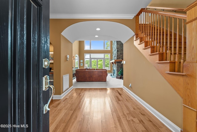 118 Douglas Dr, West End, NC 27376 - foyer featuring wood finished floors, arched walkways, a stone fireplace, ornamental molding, and stairs