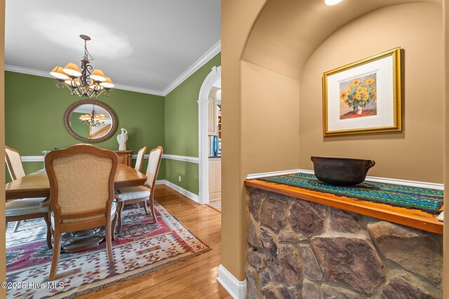 118 Douglas Dr, West End, NC 27376 - dining space featuring a chandelier, wood finished floors, arched walkways, and crown molding