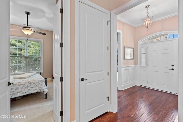 4239 Ashfield Pl, Southport, NC 28461 - foyer with ornamental molding, dark wood-style flooring, a ceiling fan, and wainscoting