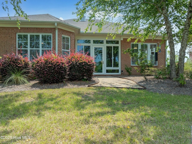4239 Ashfield Pl, Southport, NC 28461 - rear view of house featuring brick siding, a lawn, roof with shingles, and a patio