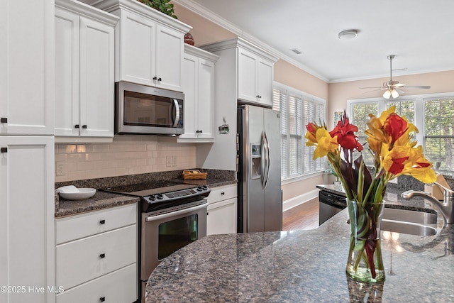 4239 Ashfield Pl, Southport, NC 28461 - kitchen with appliances with stainless steel finishes, white cabinetry, decorative backsplash, a ceiling fan, and crown molding