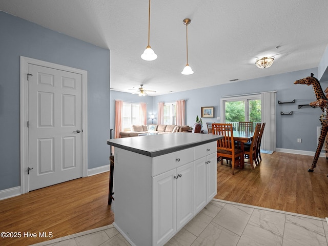 300 Lighthouse Ln Unit C2, Cedar Point, NC 28584 - kitchen featuring white cabinetry, a center island, decorative light fixtures, ceiling fan, and a textured ceiling