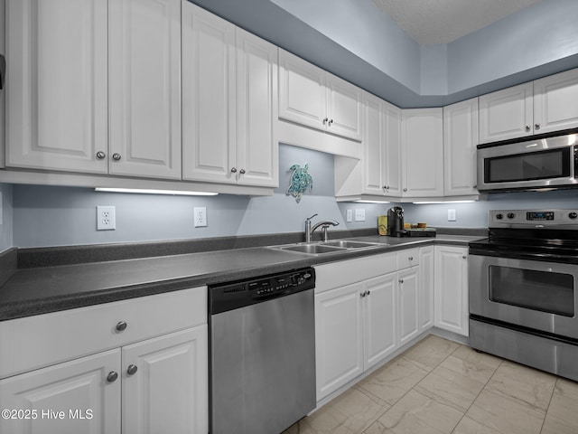 300 Lighthouse Ln Unit C2, Cedar Point, NC 28584 - kitchen with stainless steel appliances, a sink, light marble finish flooring, dark countertops, and white cabinetry