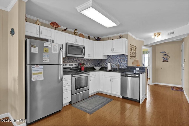101 W First St # A2, Ocean Isle Beach, NC 28469 - kitchen featuring stainless steel appliances, dark countertops, white cabinetry, and crown molding