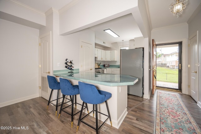 103 Continental Dr Unit 3, Elizabeth City, NC 27909 - kitchen featuring stainless steel appliances, a peninsula, dark wood-style floors, a kitchen bar, and white cabinetry