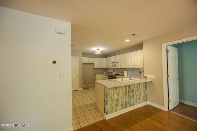 421 Commerce Ave Unit B, Morehead City, NC 28557 - kitchen with white microwave, a peninsula, stainless steel electric range oven, white cabinetry, and light countertops