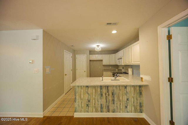 421 Commerce Ave Unit B, Morehead City, NC 28557 - kitchen featuring white microwave, a peninsula, a sink, light countertops, and white cabinets