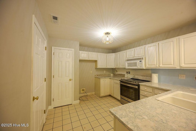 421 Commerce Ave Unit B, Morehead City, NC 28557 - kitchen with stainless steel range with electric stovetop, white microwave, light tile patterned flooring, light countertops, and white cabinetry