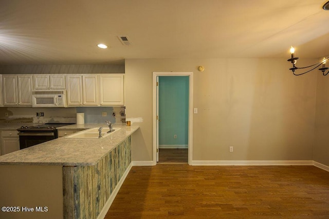 421 Commerce Ave Unit B, Morehead City, NC 28557 - kitchen with white microwave, electric range, a sink, dark wood-style flooring, and white cabinetry