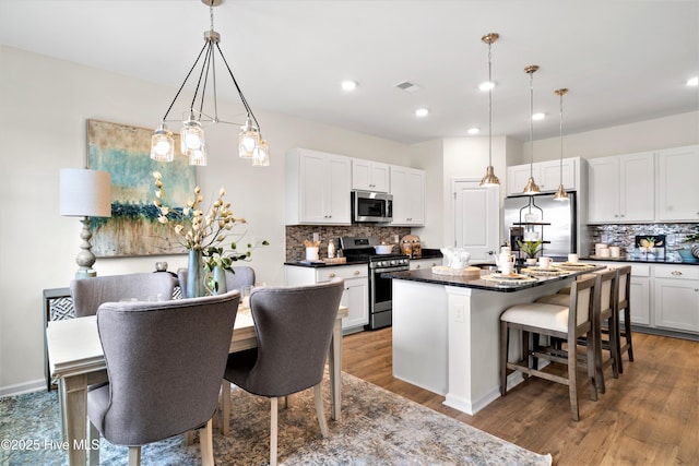 658 Edgeside Dr SE, Bolivia, NC 28422 - kitchen featuring stainless steel appliances, tasteful backsplash, a kitchen bar, wood finished floors, and white cabinetry