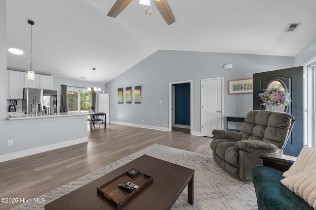 1014 Ponderosa Pl, Jacksonville, NC 28546 - living room featuring vaulted ceiling, a chandelier, a ceiling fan, light wood-style floors, and baseboards