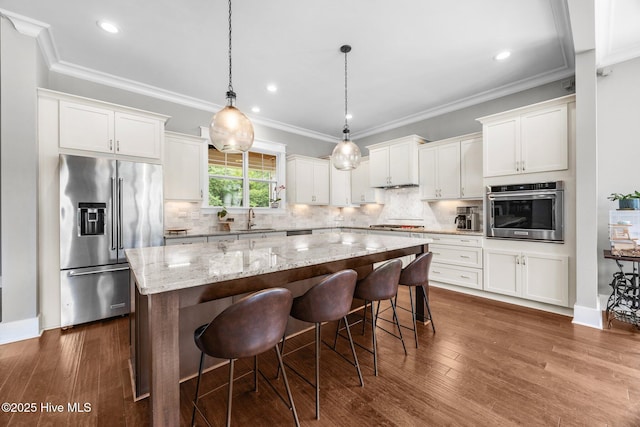 137 Summerset Lndg, Hampstead, NC 28443 - kitchen featuring appliances with stainless steel finishes, a kitchen island, white cabinetry, light stone countertops, and ornamental molding